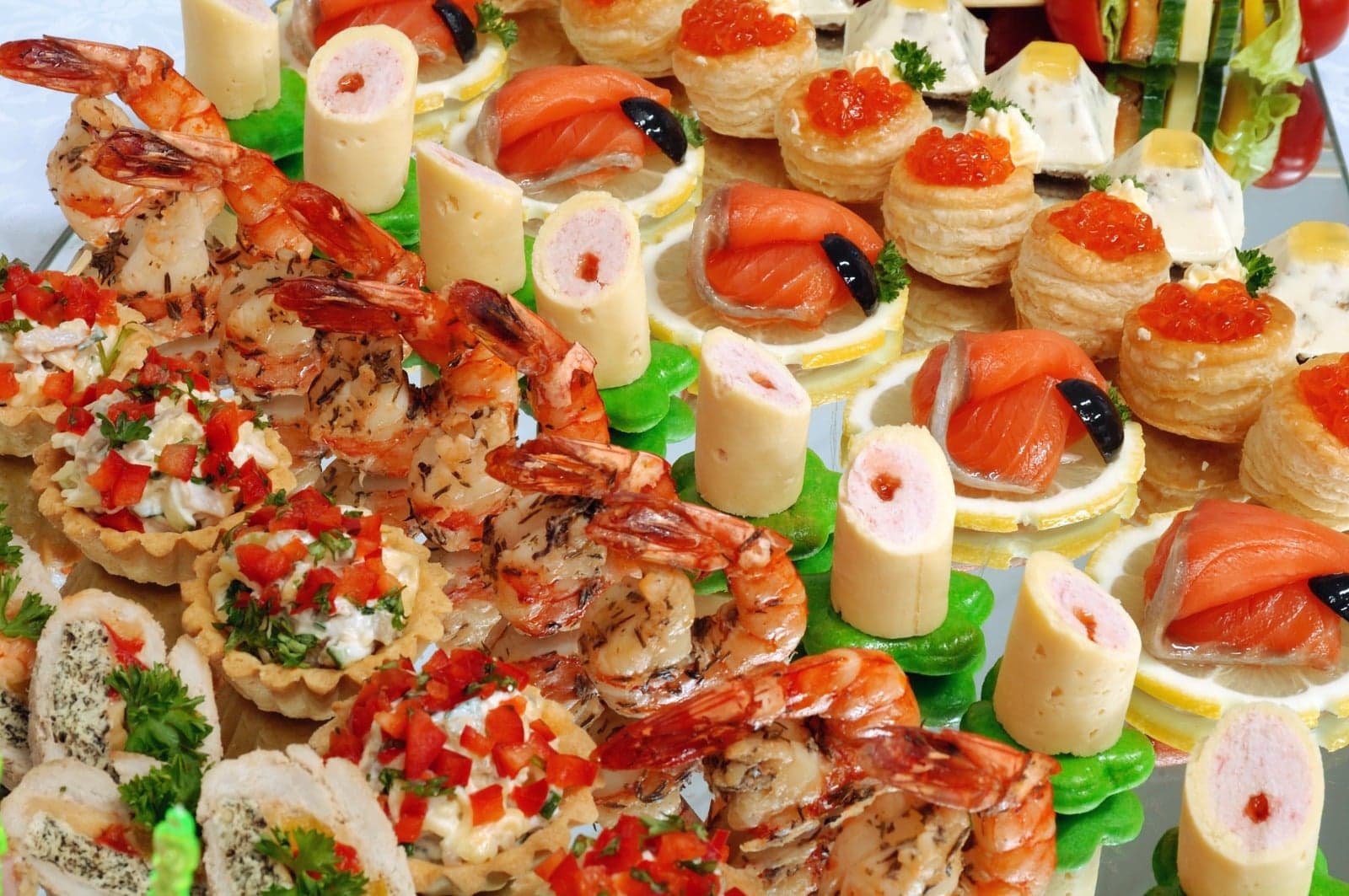 Reich belegte Fingerfood-Platte von PEC: Garnelenspieße, Lachs-Blätterteig mit Kaviar und gefüllte Törtchen